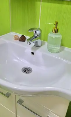 a white sink in a bathroom with green walls at Apartman Stanković in Teslić