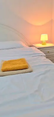 a white bed with a yellow rug on it at Apartman Stanković in Teslić