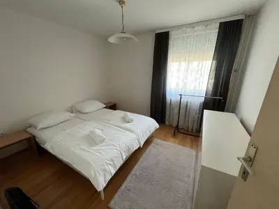 a small bedroom with a white bed and a window at Apartman Lavanda in Živinice