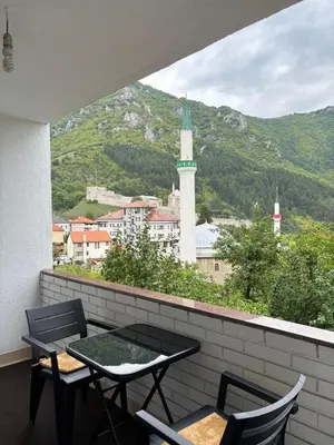 a balcony with a table and chairs and a clock tower at Apartman Kahvica in Travnik