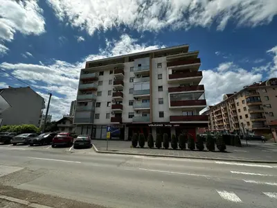 a tall building with cars parked in a parking lot at Dana'S in Doboj
