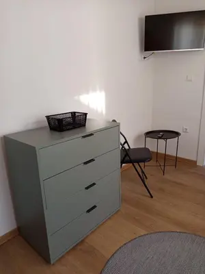a dresser in a room with a chair and a tv at Apartmani Piralis in Bihać