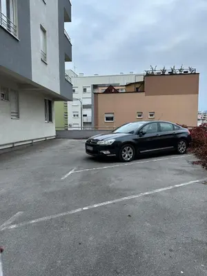 a black car parked in a parking lot next to a building at Apartman Radmanović in Banja Luka
