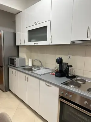 a kitchen with white cabinets and a sink and a microwave at Apartman Radmanović in Banja Luka