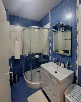 a blue tiled bathroom with a sink and a shower at Venecija Most in Banja Luka