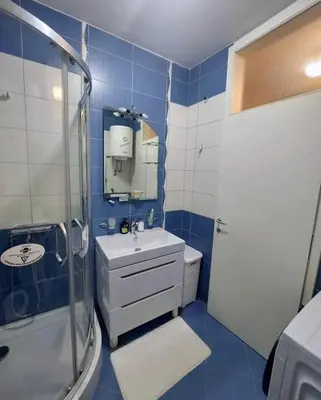 a blue and white bathroom with a sink and a shower at Venecija Most in Banja Luka