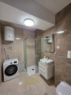 a bathroom with a shower sink and a washing machine at Apartman RS Palata in Banja Luka