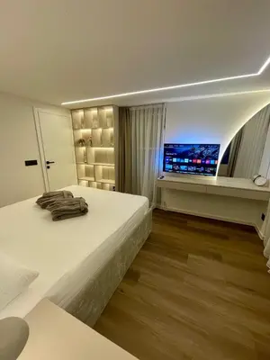a bedroom with a large white bed and a television at Villa Evora in Banja Luka