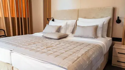 a bedroom with a large bed with white sheets and pillows at Hotel Branch in Doboj