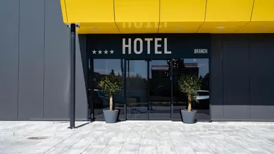 a hotel building with two potted trees in front of it at Hotel Branch in Doboj
