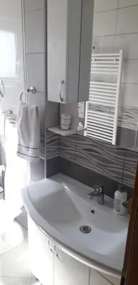 a white bathroom with a sink and a mirror at Apartman Iris in Bosanski Brod