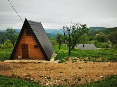 a small house with a black roof in a field at Naša Maša Doboj- bungalov Nasa Masa Doboj-bungalov in Doboj