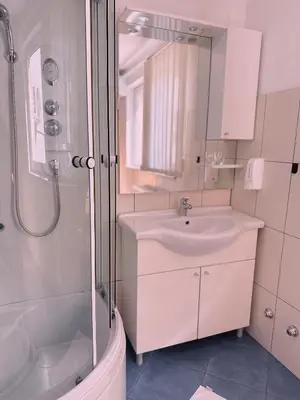a white bathroom with a sink and a shower at Layal Home in Bihać