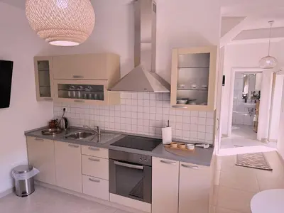 a kitchen with white cabinets and a stove top oven at Layal Home in Bihać