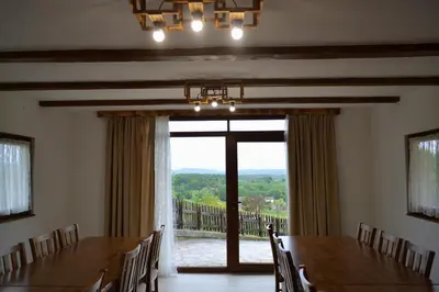 a dining room with a large window and a table and chairs at Ranč Kuzmanović in Doboj