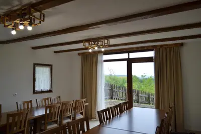 a dining room with a table and chairs and a large window at Ranč Kuzmanović in Doboj