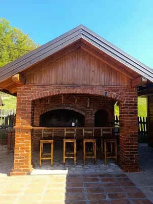 a brick pavilion with chairs and a table in it at Ranč Kuzmanović in Doboj