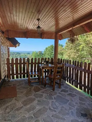 a porch with a table and chairs and a view at Ranč Kuzmanović in Doboj