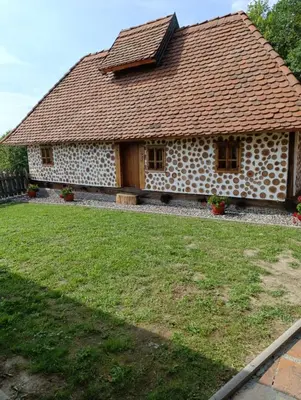 a stone house with a tile roof on a yard at Ranč Kuzmanović in Doboj