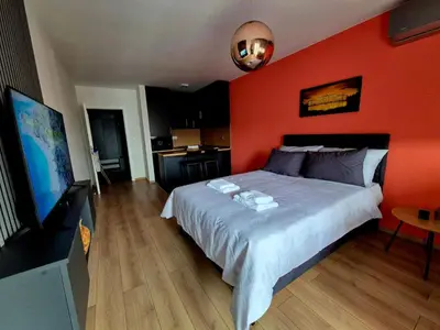 a bedroom with a large bed with an orange wall at Apartman Belvedere Lux, Doboj in Doboj