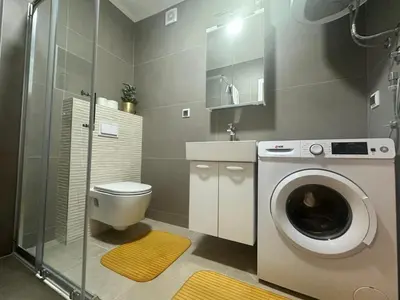 a bathroom with a washing machine and a toilet at Apartman Belvedere Lux, Doboj in Doboj