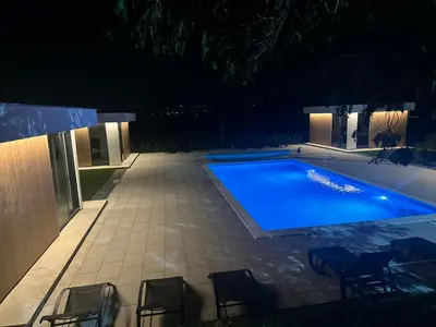 a swimming pool at night with chairs around it at Apartments Daisy in Banja Luka