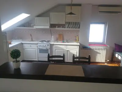a kitchen with white cabinets and a table and chairs at Apartment Nedic in Doboj