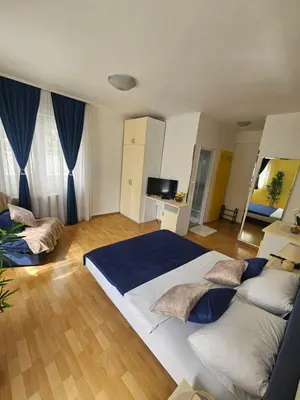 a large bedroom with a large bed and blue curtains at Rooms MIG in Banja Luka