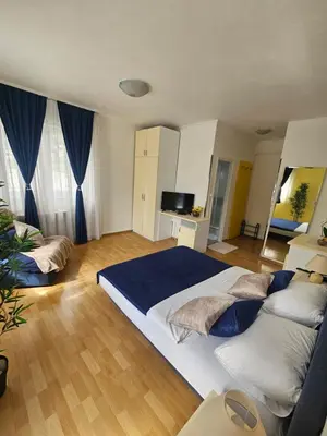 a large bedroom with two beds and blue curtains at Rooms MIG in Banja Luka
