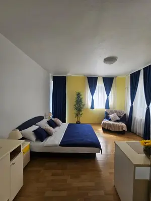 a bedroom with a large bed and blue curtains at Rooms MIG in Banja Luka