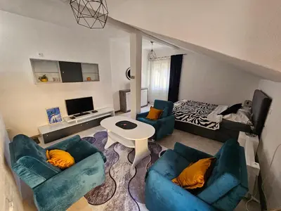 a living room with two blue couches and a bed at Apartmani S Banja Luka in Pištelići
