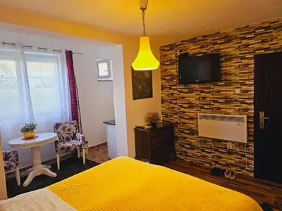 a bedroom with a yellow bed and a tv on a brick wall at Apartmani S Banja Luka in Pištelići