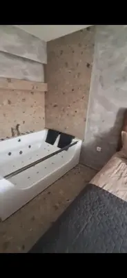 a bathroom with a white bath tub next to a bed at Relax Apartman DMBL in Banja Luka