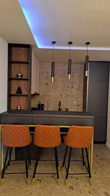 a kitchen with a counter and some orange chairs at Relax Apartman DMBL in Banja Luka