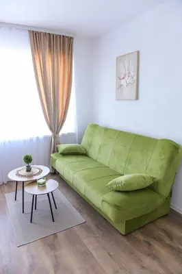 a green couch in a living room with a table at Stan na dan-Studio 10 centar Gradiška in Bosanska Gradiška