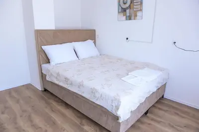 a bed in a room with white walls and wooden floors at Stan na dan-Studio 10 centar Gradiška in Bosanska Gradiška