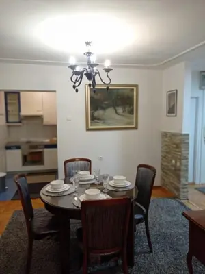 a dining room table with chairs and a chandelier at Apartman Centar in Banja Luka