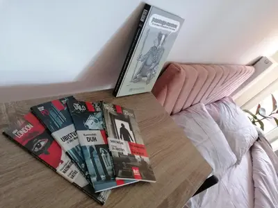 a pile of books on a table next to a bed at iwe in Banja Luka