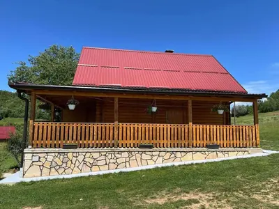 a large wooden cabin with a red roof at Vikendica Neprivaj in Vareš