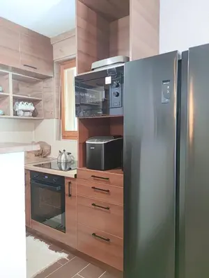 a stainless steel refrigerator in a kitchen with wooden cabinets at Villa Kamenica in Zavidovići