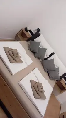 a bed with three pillows on top of it at Apartman Leky in Tuzla
