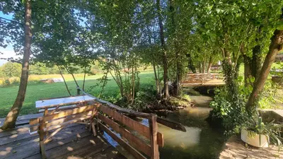 a wooden bridge over a river with a swing at Simetić