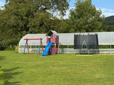a playground in a field with a tent at Simetić