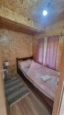 a bedroom with a bed with pink sheets and a ceiling at Simetić