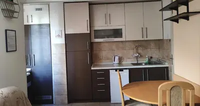 a small kitchen with white cabinets and a table at Sunny Banja Luka in Banja Luka