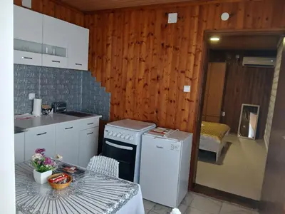 a kitchen with a table and a stove and a sink at Studio apartman MA Kostajnica in Kostajnica