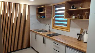 a kitchen with white cabinets and a sink and a window at Kovačnica 55