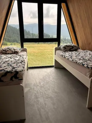 two beds in a room with large windows at A Frame house Slavuljica in Vlasic