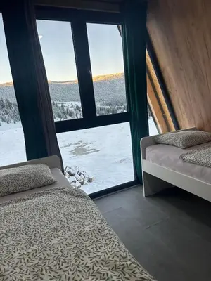 a room with two beds and a window with snow outside at A Frame house Slavuljica in Vlasic