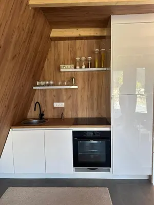 a kitchen with white cabinets and a black oven at A Frame house Slavuljica in Vlasic